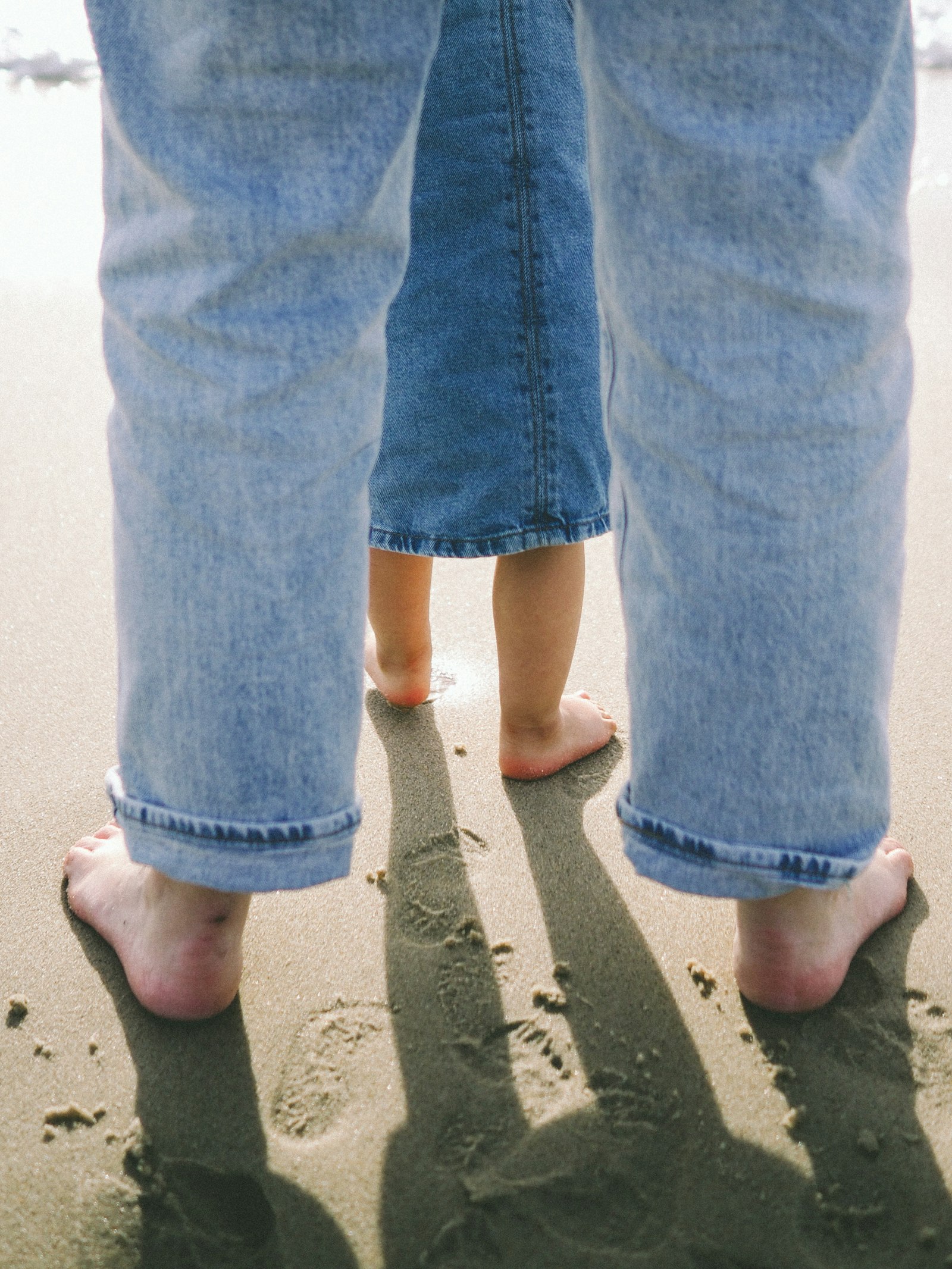 Parent and child barefoot in the sand on a Portugal beach near Caldas da Rainha